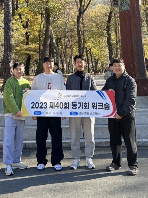Members of the WorldSkills Champions’ Association of Korea stand with a banner in a park.