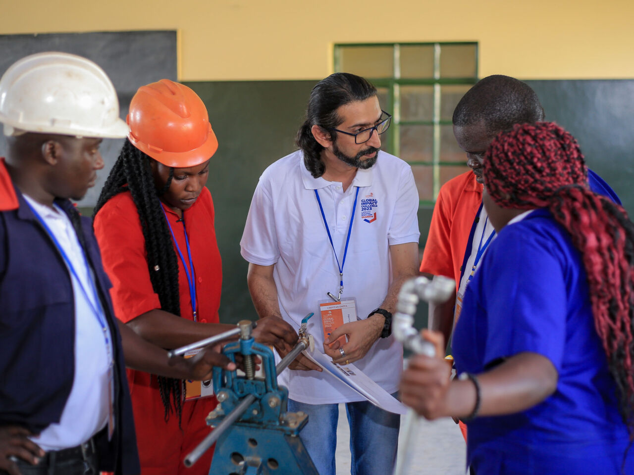 Participants of the Global Impact Challenge programme Ugandan capacity building bootcamp in May 2023 discuss plans with a VET trainer.
