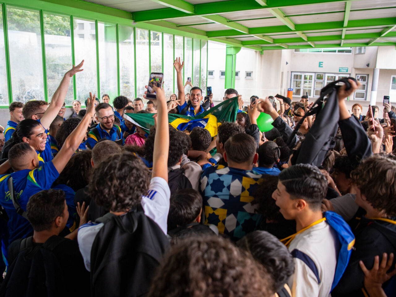 A crowd of school children flock around Competitors visiting their school on 10 September 2024 as part of the cultural exchange programme One School One Country (OSOC).
