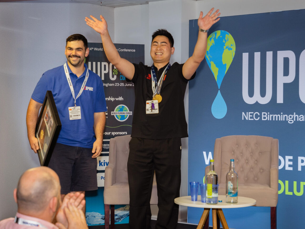 A participant raises his arms on stage during the Skills Forum event at the World Plumbing Conference in June 2026.
