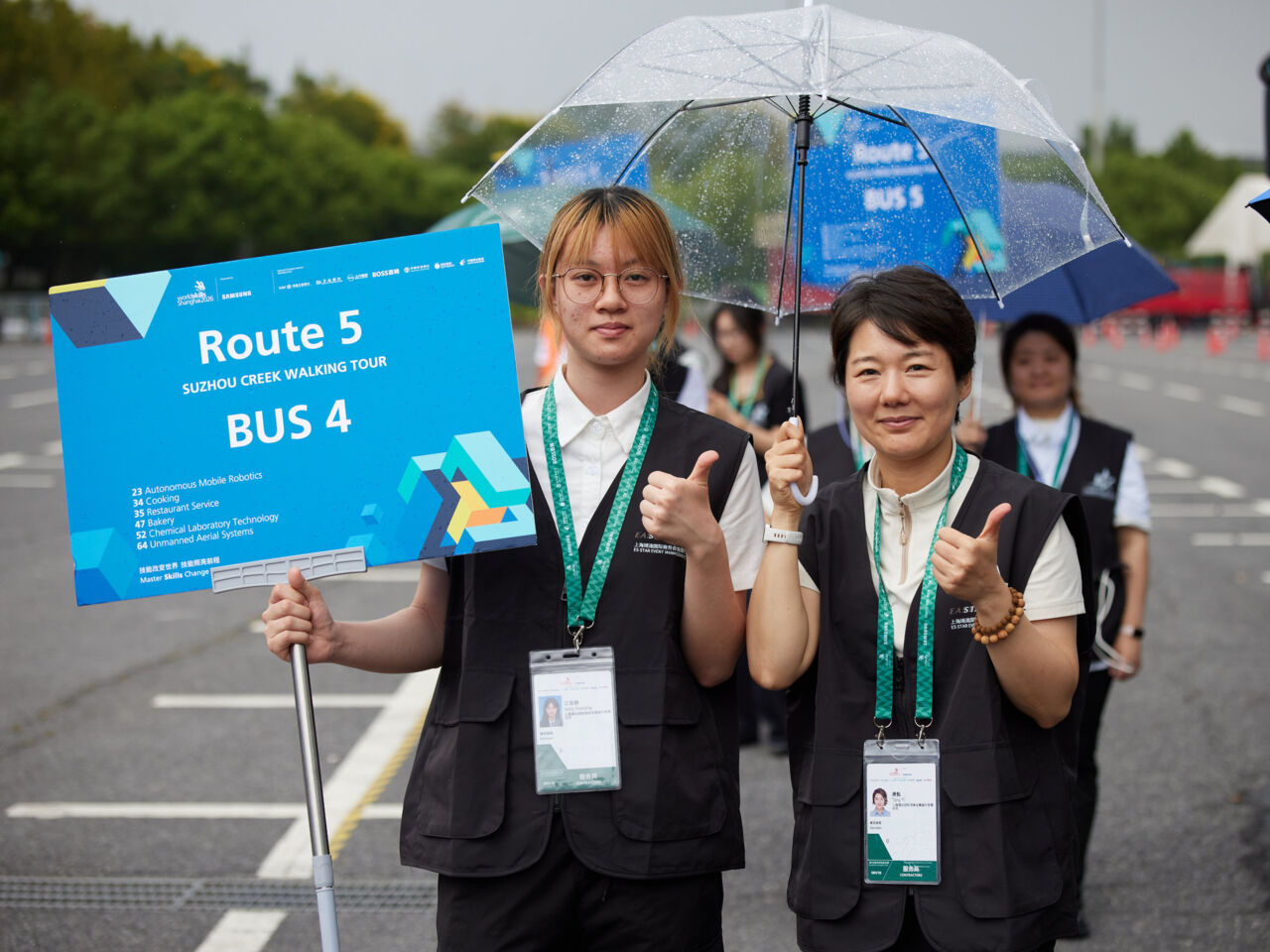 Volunteers give a thumbs up while guiding people around WorldSkills Shanghai 2026.
