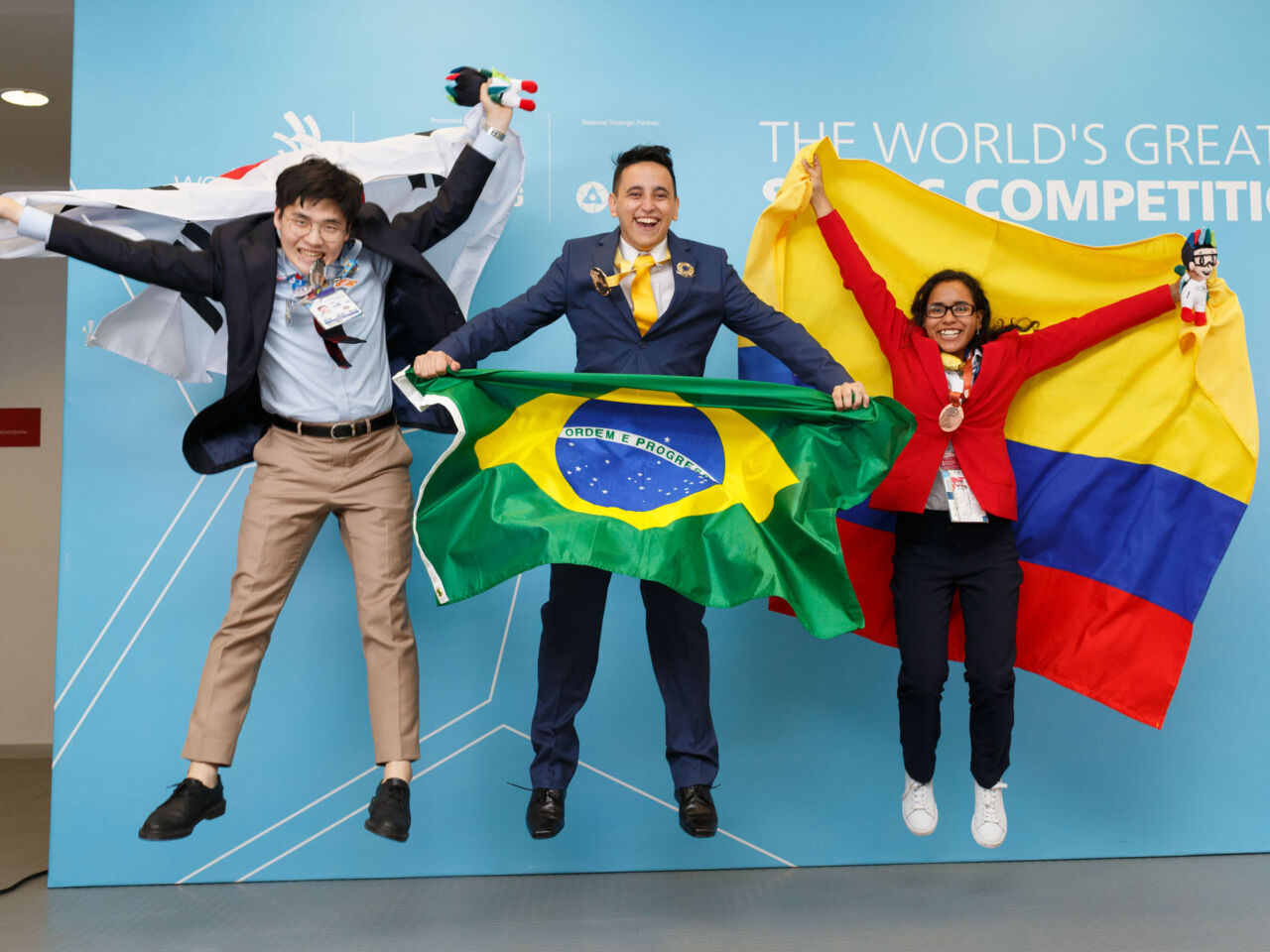 Jenifer Cardona Guevara celebrates by leaping into the air with fellow medal winners in the skill of Mechanical Engineering CAD at WorldSkills Kazan 2019.