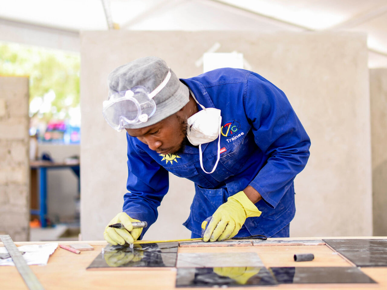 A competitor leaning over a workbench doing close work on tiles during Ongwediva 2023 (NSCO2023), Namibia’s third National Skills Competition taking place from 25 to 30 September 2023.