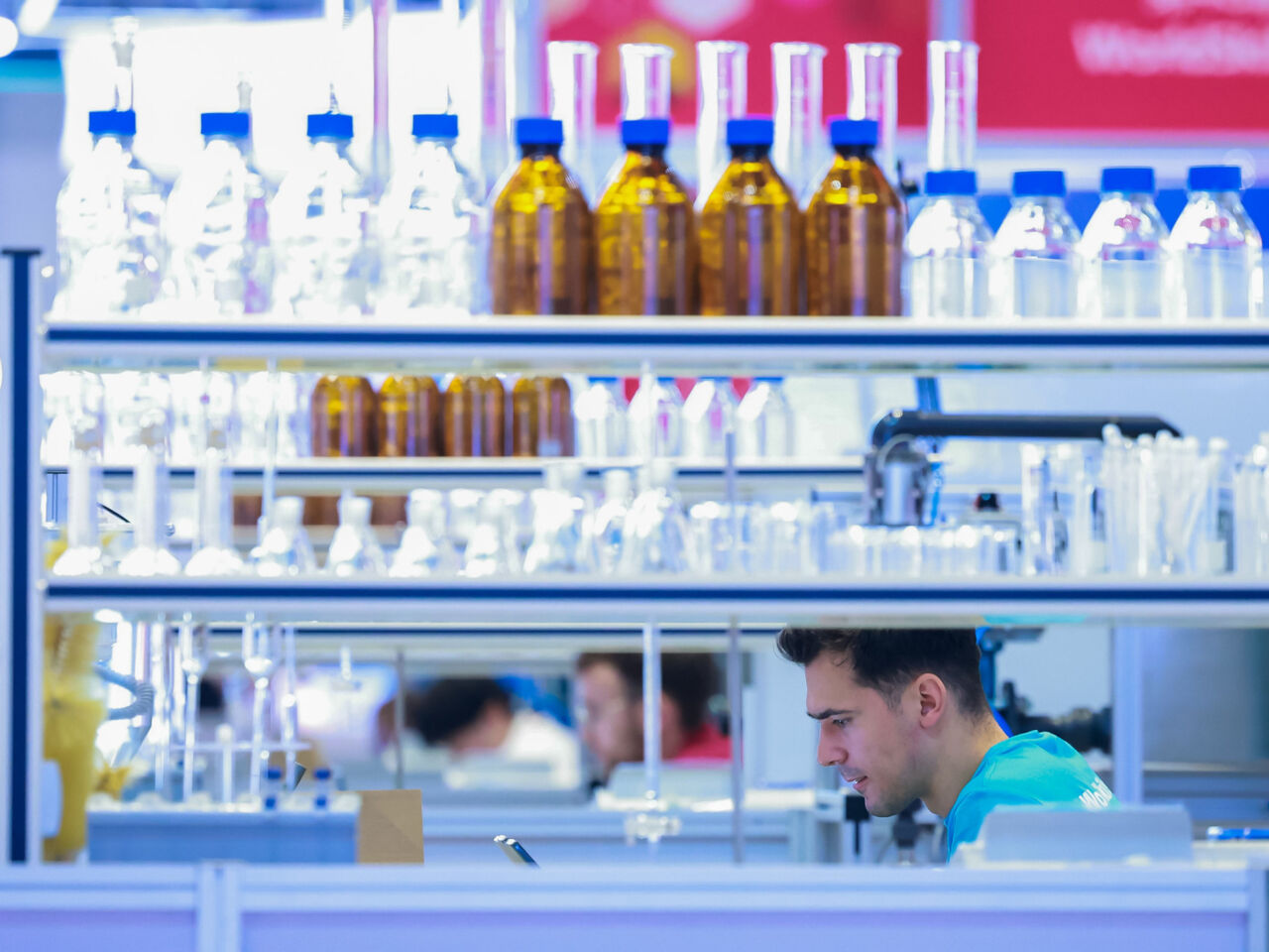 A Competitor in Water Technology glimpsed through the gap in rows of glass bottles on day 1 of competition at WorldSkills Shanghai 2026..