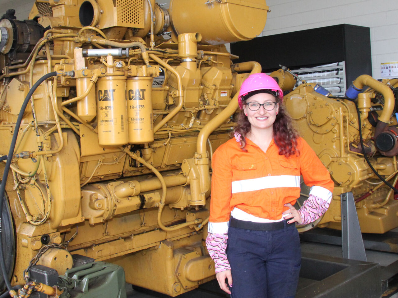 Louise Azzopardi, a mechanic from Australia, standing in front of heavy machinery.