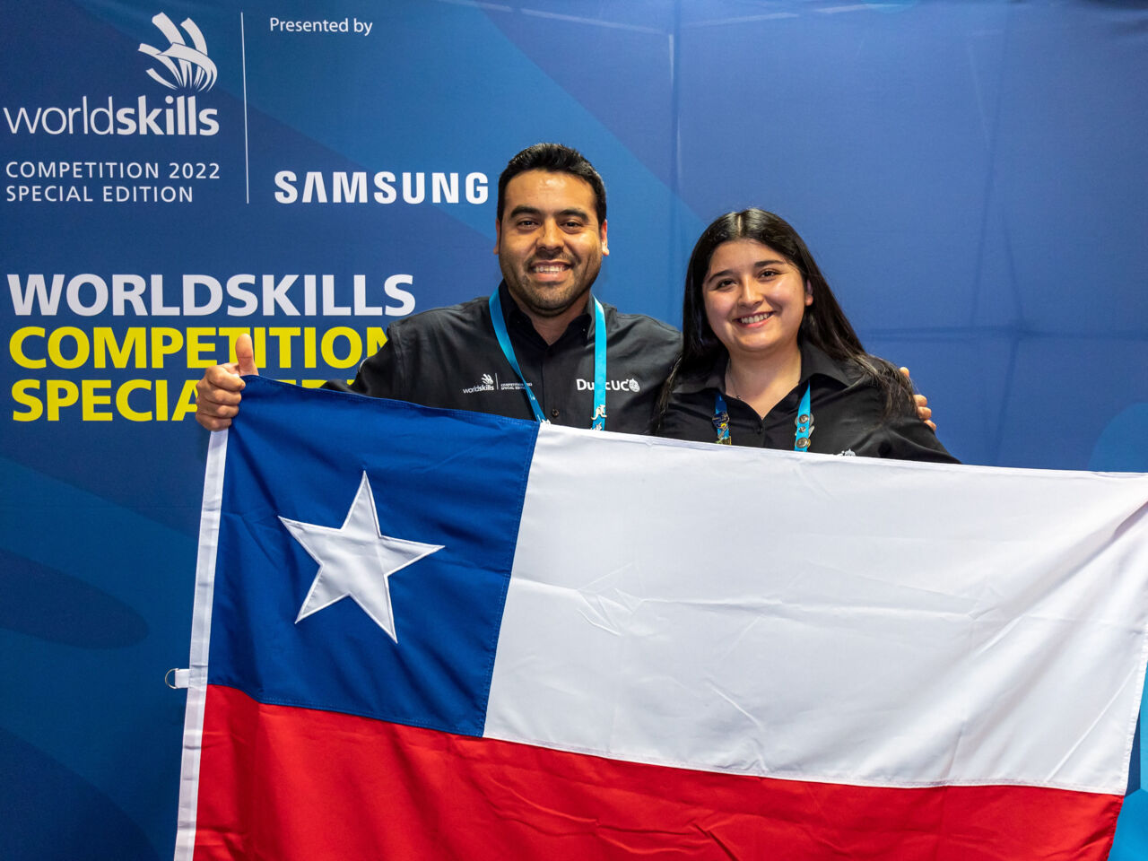 María Belén Almonacid Barros, the first Chilean female Competitor in the Automotive Technology, stands with her country's flag at WorldSkills Competition 2022 Special Edition.