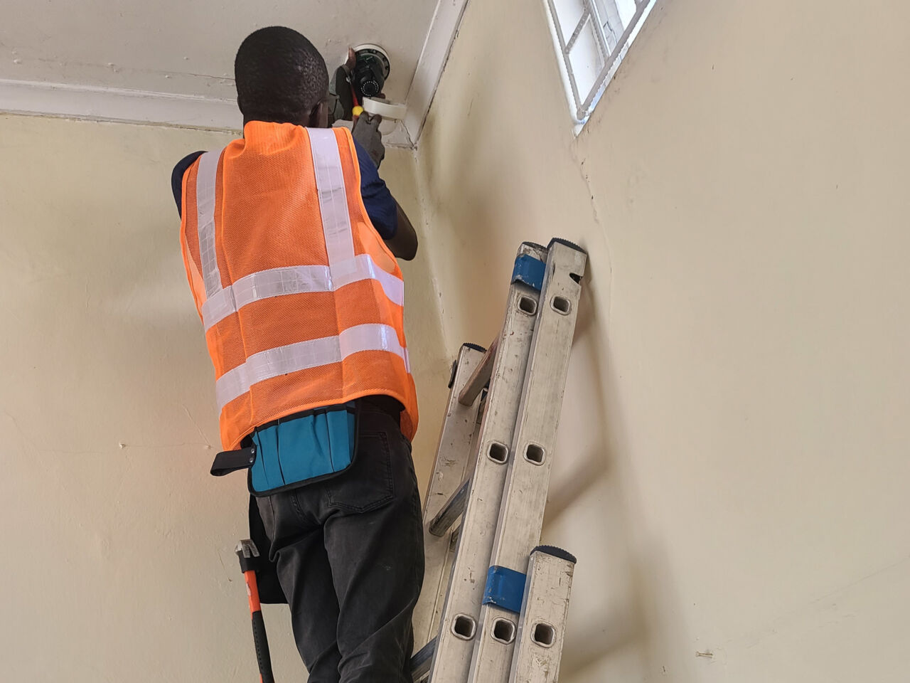 Abraham Mundengo from Zambia climbing a ladder and using his Information Network Cabling skills to install internet access.